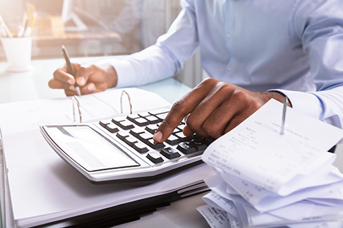 Close-up,Of,A,Businessman,Calculating,Invoice,Using,Calculator,At,Workplace After starting up a new company, monthly costs can catch you by surprise if you don’t plan carefully. As a business owner, you will want to be aware of these.